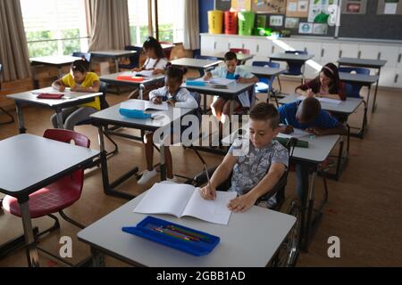 Eine Gruppe verschiedener Schüler, die in der Schule auf ihrem Schreibtisch sitzen und studieren Stockfoto