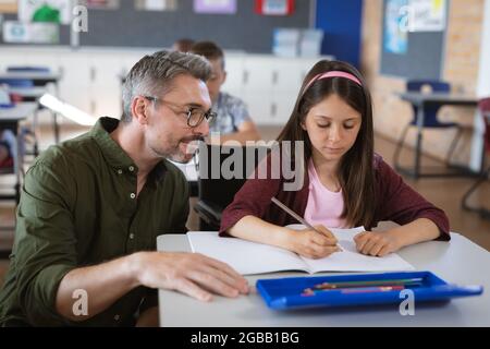 Kaukasischer Lehrer, der kaukasisches Mädchen in der Schule unterrichtet Stockfoto