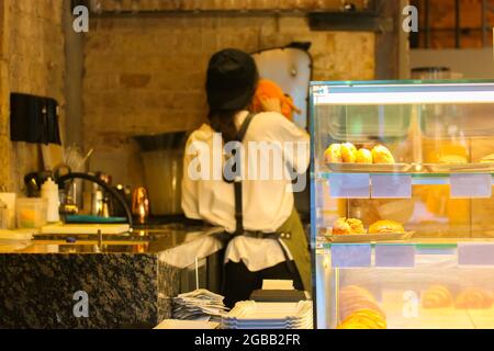 Eine Barista aus der Rückansicht bereitet Orangensaft zu. Ein nicht erkennbarer Kaffeehaus. Stockfoto