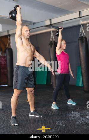 Starke kaukasische Männer und Frauen trainieren im Fitnessstudio und heben Gewichte Stockfoto
