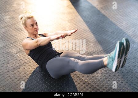 Starke kaukasische Frau, die im Fitnessstudio trainiert, Sit-ups macht Stockfoto