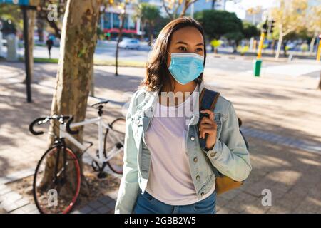 Asiatische Frau trägt Gesichtsmaske zu Fuß in sonnigen Park Stockfoto