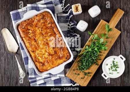 Pikante Kartoffel-kugel, gebackener Pudding oder Auflauf geriebener Kartoffel in einer Auflaufform auf einem Holztisch, jüdisches Feiertagsrezept, flaches Lay Stockfoto