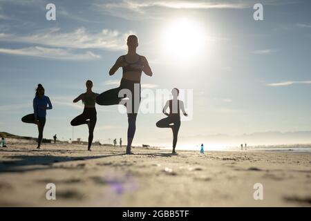 Eine Gruppe verschiedener Freundinnen, die am Strand Yoga praktizieren Stockfoto