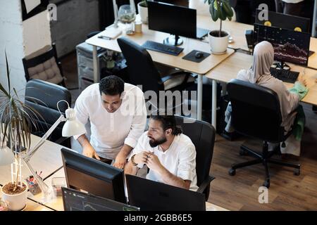Zwei Geschäftsleute diskutieren Daten auf dem Computerbildschirm, während sie im Büro arbeiten Stockfoto