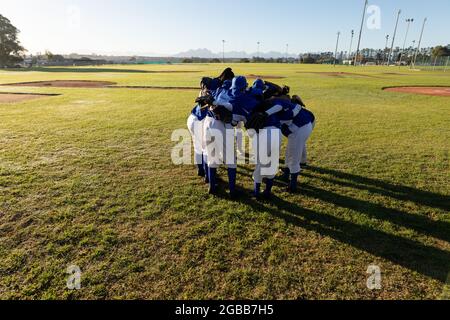 Verschiedene Gruppen von Baseballspielerinnen, die auf dem Baseballfeld in Huddle stehen Stockfoto