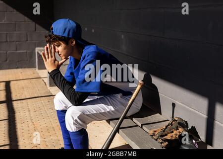 Gemischtes Rennen weibliche Baseballspielerin sitzt auf der Bank mit Fledermaus Vorbereitung auf das Spiel während des Spiels Stockfoto