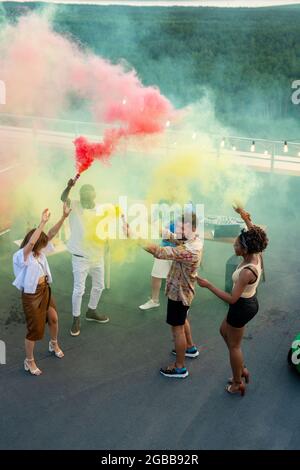 Moderne junge, ekstatische Menschen tanzen auf der Terrasse, während sie eine Dachparty genießen Stockfoto