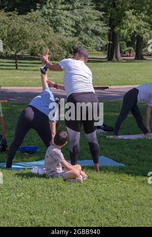 Ein Yoga- und Wellnesslehrer mittleren Alters, der einen Schüler in einer Klasse im Flushing Meadows Corona Park in Queens, New York City, unterrichtet. Stockfoto