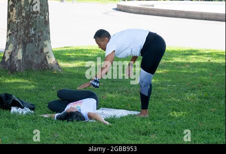 Ein Yoga- und Wellnesslehrer mittleren Alters, der einen Schüler in einer Klasse im Flushing Meadows Corona Park in Queens, New York City, unterrichtet. Stockfoto