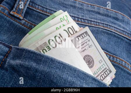 Dollar und Euro ragen aus der Jeans-Tasche Stockfoto