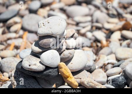 Ausgewogene Kieselsteinpyramide am Strand an einem sonnigen Tag. Meditation, Balance, Ruhe und Harmonie Konzept. Stockfoto