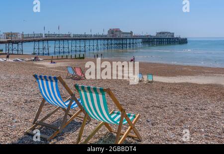 Blick auf Worthing Pier und bunte Liegestühle am Worthing Beach, Worthing, West Sussex, England, Vereinigtes Königreich, Europa Stockfoto
