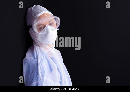 Frau in medizinischen Geräten und Brillen mit müdem Aussehen posiert in Pandemiezeiten vor der Kamera. Stockfoto