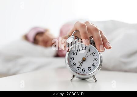 Die Dame liegt auf dem Bett und versucht aufzuwachen, steht früh auf, um zu arbeiten Stockfoto