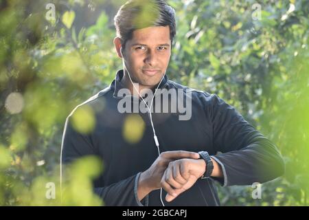 Lächelnder Mann mit Smartwatch und Überprüfung der körperlichen Aktivität Stockfoto