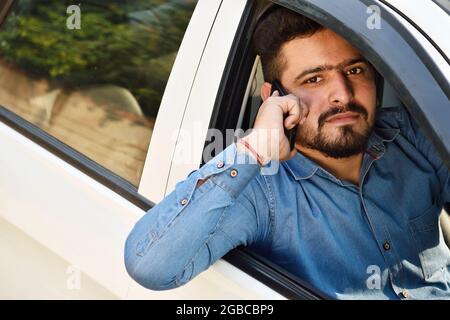 Junger Mann, der telefoniert und Auto fährt, Risiko Stockfoto