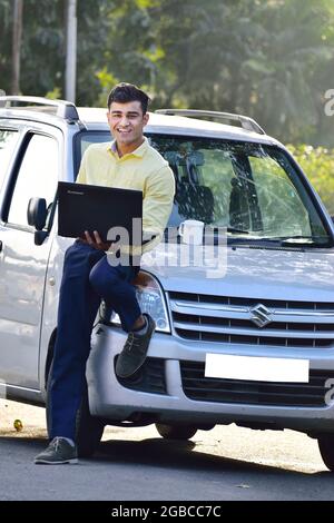 Indischer Mann, der im Freien am Laptop arbeitet, glücklicher indischer Geschäftsmann Stockfoto