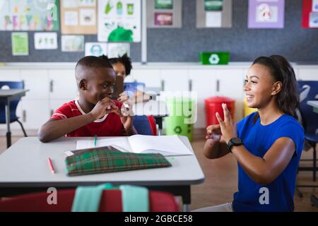 afroamerikanische Lehrerin und Junge sprechen in der Hand Gebärdensprache in der Grundschule Stockfoto