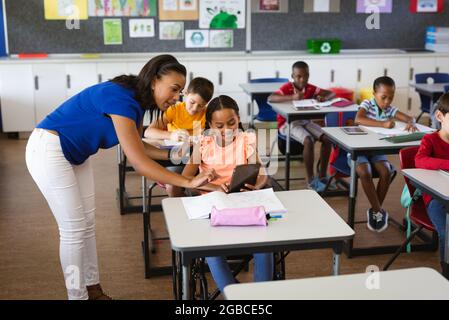 afroamerikanische Lehrerin, die behinderte Mädchen unterrichtet, um digitale Tablette an der Grundschule zu verwenden Stockfoto