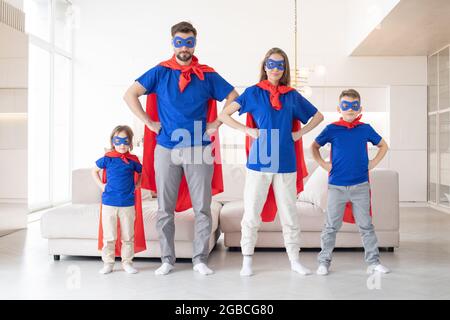 Porträt einer Familie, die vorgibt, im Wohnzimmer zu Hause Superhelden zu sein Stockfoto