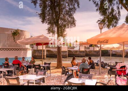 Riverside Cafe Restaurant am Fluss Gilao Tavira. Im Hintergrund ist die römische Brücke oder Ponte Romana de Tavira zu sehen. Tavira East Alga Stockfoto