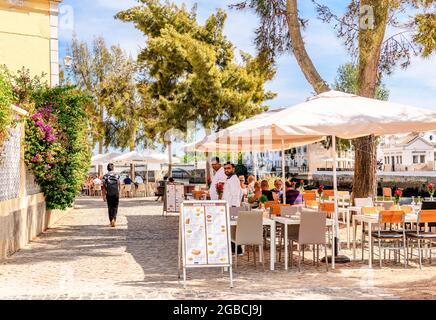 Indisches Cafe-Restaurant am Fluss Gilao Tavira. Im Hintergrund ist die römische Brücke oder Ponte Romana de Tavira zu sehen. Tavira Ea Stockfoto