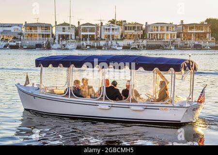 Newport Beach California, Newport Bay Balboa Bay Club & Resort, Firmenrefugium Duffy Electric boat Riders Passagiere Häuser Residenzen, Stockfoto