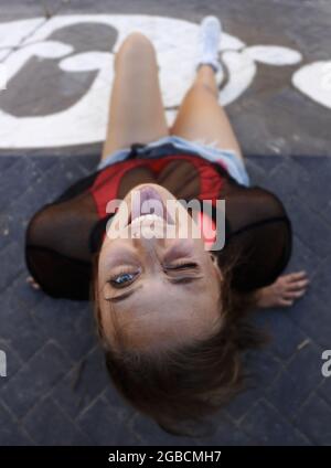 Frau im schwarzen ärmellosen Hemd auf Betonboden liegend Stockfoto