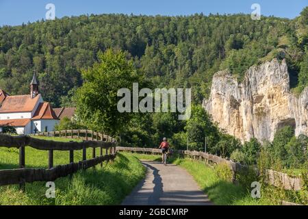 Schöne aktive Seniorin, die mit ihrem Elektro-Mountainbike im felsigen Oberen Donautal auf der Schwäbischen Alb zwischen Beuron und Sigmaring unterwegs ist Stockfoto