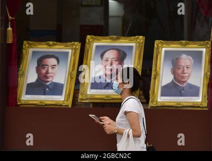 Peking, China. August 2021. Ein Tourist, der als Vorsichtsmaßnahme gegen die Verbreitung von covid-19 eine Gesichtsmaske trägt, geht an den Porträts von Mao Zedong vorbei, die im Fenster des Pekinger Fotostudios in der Wangfujing Commercial Street aufgestellt wurden. (Foto von Sheldon Cooper/SOPA Images/Sipa USA) Quelle: SIPA USA/Alamy Live News Stockfoto