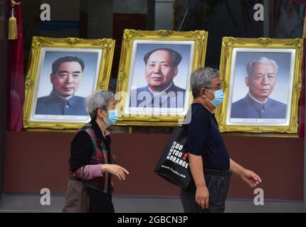 Peking, China. August 2021. Ein paar Touristen, die Gesichtsmasken tragen, als Vorsichtsmaßnahme gegen die Verbreitung von covid-19, gehen an den Porträts von Mao Zedong vorbei, die im Fenster des Pekinger Fotostudios in der Wangfujing Commercial Street aufgestellt wurden. (Foto von Sheldon Cooper/SOPA Images/Sipa USA) Quelle: SIPA USA/Alamy Live News Stockfoto