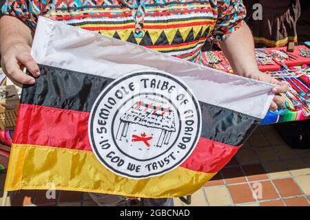 Miami Florida,Cultural Center Plaza Entdecken Sie Miami Fair,Miccosukee Seminole indianische Indianerin, Stammesflagge, Frau, die Holding zeigt Stockfoto