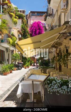 Taormina, Messina, Sizilien, Italien. Eine charmante, mit Blumen gefüllte Ecke der Altstadt, typische Trattoria im Vordergrund mit Tischen zum Mittagessen. Stockfoto