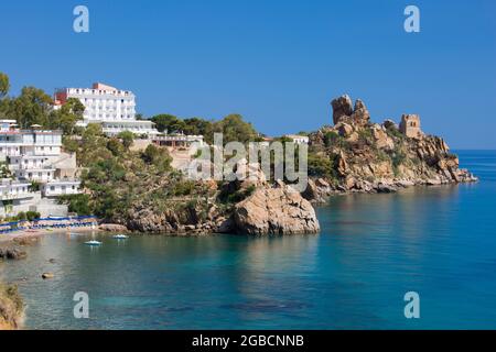 Cefalù, Palermo, Sizilien, Italien. Blick über das ruhige, türkisfarbene Wasser der Calura Bay, ein antiker steinerner Wachturm, der auf der Landzunge sichtbar ist. Stockfoto