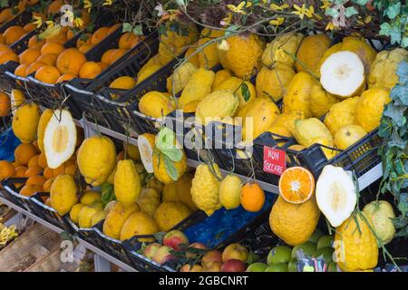 Taormina, Messina, Sizilien, Italien. Typische Zitrusfrüchte, die vor dem Laden des Gemüsehaums in der Altstadt ausgestellt werden, ganze und abgeteilte Zitronen sind prominent. Stockfoto