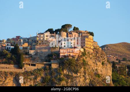 Taormina, Messina, Sizilien, Italien. Blick auf das hübsche mittelalterliche Dorf Castelmola, Sonnenaufgang, prekär thronende Häuser, die sich an einer Klippe Klammern. Stockfoto