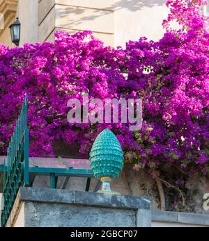 Taormina, Messina, Sizilien, Italien. Rosafarbene Bougainvillea schmückt eine Straßenecke der Altstadt hinter einer exquisiten Keramikvase in Form eines Pinienkegels. Stockfoto