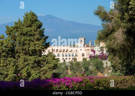 Taormina, Messina, Sizilien, Italien. Blick auf das San Domenico Palace Hotel und die hoch aufragenden Hänge des Ätna von den Gärten der Villa Comunale. Stockfoto