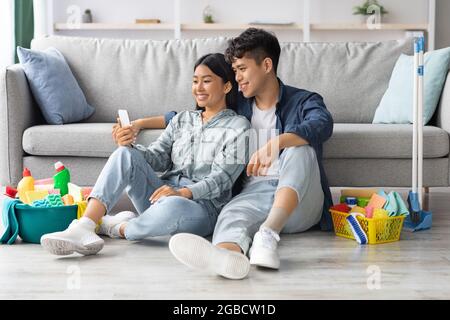 Niedlich asiatische paar mit Handy mit Pause nach der Reinigung Stockfoto
