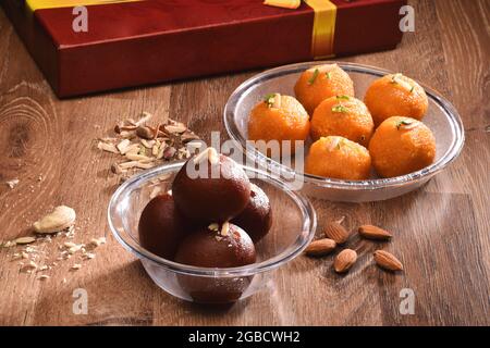 diwali Süßwaren-Konzept, Ladoo und Gulab Jamun auf Holztisch mit Süßwaren-Box im Hintergrund Stockfoto