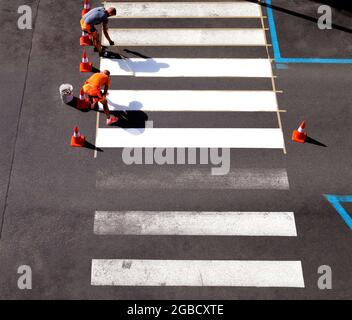 Arbeiter malen Streifen mit weißer Farbe. Stockfoto