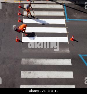 Arbeiter malen Streifen mit weißer Farbe. Stockfoto