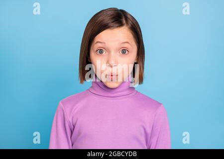 Foto von charmanten beeindruckt Schulmädchen tragen lila Rollkragen großen Augen Lippen pouted isoliert blaue Farbe Hintergrund Stockfoto