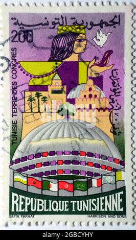 Eine von Tunesien gedruckte Briefmarke zeigt den Kongresspalast 200, um 1986, die Briefmarke zeigt eine Kuppel, eine Dame und einige arabische Länderflaggen, Tunis Stockfoto