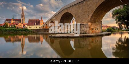 Regensburg, Deutschland. Panoramabild von Regensburg, Deutschland mit der alten Steinbrücke über die Donau und dem Petersdom bei Sonnenuntergang im Sommer. Stockfoto