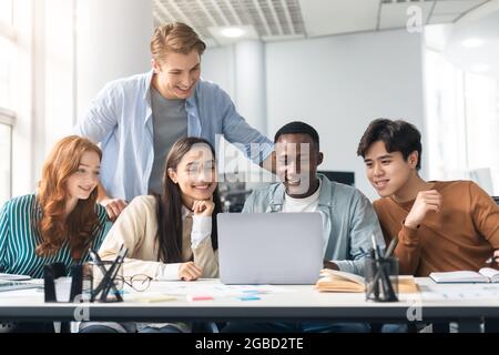 Gruppe von internationalen Personen, die im Klassenzimmer einen Laptop benutzen Stockfoto