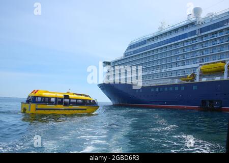 Schiff vor Anker im St. Peter Port, Guernsey. Großes Schiff mit blauem Rumpf und einem gelben Rettungsboot oder Tender vor der Küste, Kanalinseln, großbritannien. Stockfoto