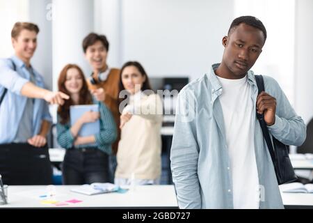Die Leute spotten und machen sich über den traurigen afrikanischen Mann lustig Stockfoto