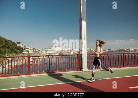 Sportlerin mit fliegenden Haaren läuft an sonnigen Tagen über den Steg Stockfoto